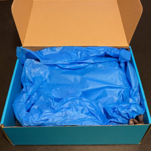 Light blue cardboard box open to reveal blue tissue paper